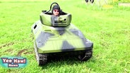 Ein Mann sitzt in einem Minipanzer.  