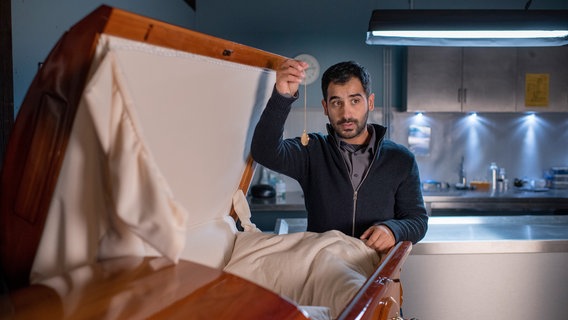 Friedhofsgärtner David Musisi (Tanju Bilir) macht sich an einem bereits verkauften Sarg zu schaffen. © ARD/Thorsten Jander 