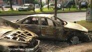 Zwei ausgebrannte Autos stehen am Straßenrand  