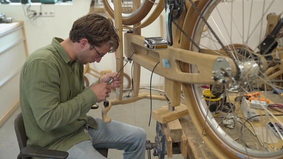 Ein Mann werkelt an einem Fahrrad komplett aus Holz. © NDR 