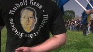Ein NSU Mitglied steht mit dem Rücken zur Kamera. Die Aufschrift auf seinem T-Shirt: Rudolf Hess - Märtyrer des Friedens  