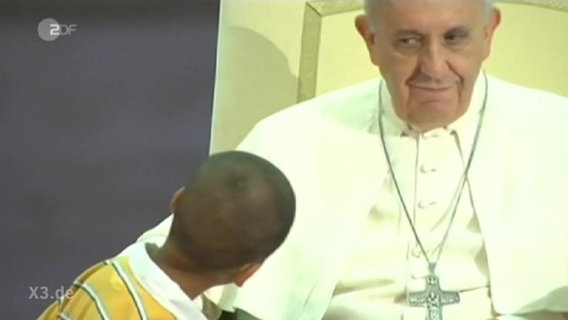 Ein Kind blickt den Papst an.  