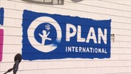 Das Logo von "Plan International" auf einer Wand.  