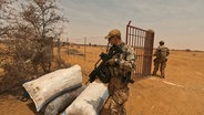 Ein bewaffneter Bundeswehrsoldat steht vor einem Haufen Säcke. © Marco Schulze, Johannes Koch Foto: Marco Schulze, Johannes Koch