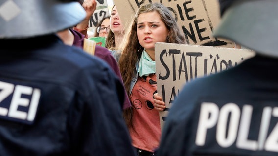 Ein junges Mädchen befindet sich in einer Gruppe von Demonstrierenden. Vor ihr stehen zwei Polizisten. © ARD/Steffen Junghans Foto: Steffen Junghans