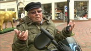 Ein Herr beschwert sich in der Schleswiger Fußgängerzone über die örtliche Situation.  