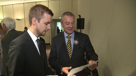 Schlegl überreicht einem Politiker der FDP eine Urkunde.  