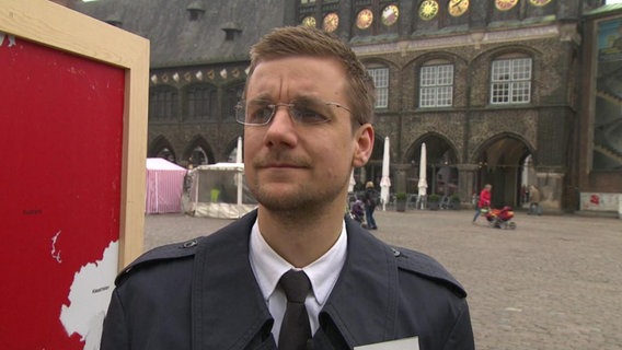 Der NDR-Reporter Tobias Schlegl steht vor dem Lübecker Rathaus.  