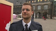 Der NDR-Reporter Tobias Schlegl steht vor dem Lübecker Rathaus.  