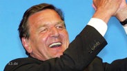 Gerhard Schröder hebt triumphierend die Arme.  