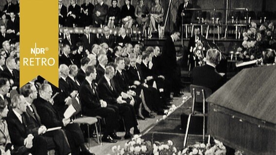 Trauergäste in einer Veranstaltung für den verstorbenen NDR-Intendanten Hilpert, rechts im Bildanschnitt der Sarg (1962).  