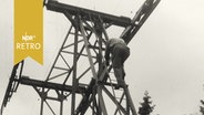 Bauarbeiter steigt am Mast einer Seilbahn herab (1962)  
