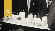 Käseplatte zum Silvesterempfang der LPK Kiel 1962 wird von zwei Männern hereingetragen.  