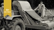 Landwirte auf einem Trecker und einer Bohnenerntemaschine 1962.  