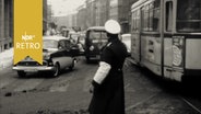 Verkehrspolizist regelt den Verkehr neben einer Straßenbahn (Hannover 1963).  