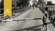 Eine Brückenwärterin schließt den Schlagbaum an einer Klappbrücke über die Stör (1965)  