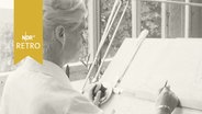 Architektin beim Zeichnen an einer Staffelei (1965)  