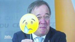 NRW-Ministerpräsident Armin Laschet hält einen weinenden Smiley in die Kamera.