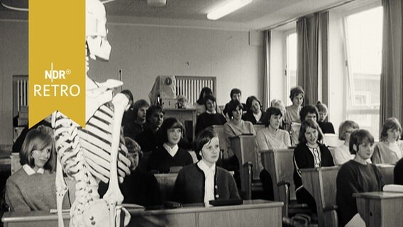 Mädchenklasse im Unterrichtsraum, im Vordergrund ein Skelett (1965)  