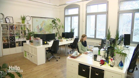 Eine junge Frau sitzt alleine im Büro, während alle KollegInnen aus dem Homeoffice arbeiten.  