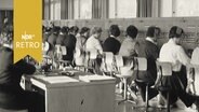 Flensburger Bundespost: Mitarbeiterinnen des Telegrafenamtes sitzen in einer langen Reihe bei der Arbeit (1961)  