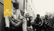Jugendliche (Lehrlinge) sitzen vor einem Gebäude (1964)  