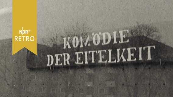 Schriftzug "Komödie der Eitelkeit" spiegelt sich in einem Schaufenster (1965)  