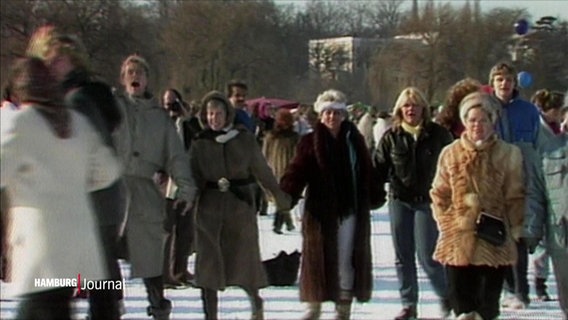 Eine alte Aufnahme von Menschen, die auf der zugefrorenen Alster spazieren gehen.  