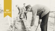 Mehrere Bauarbeiter beim Betonieren eines Grabens oder Längsschachtes 1965  