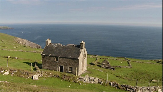 Ein wettergegerbtes Steinhaus steht an der irischen Küste.  