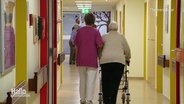 Themenbild: Eine alte Frau wird in einem Pflegeheim begleitet.  