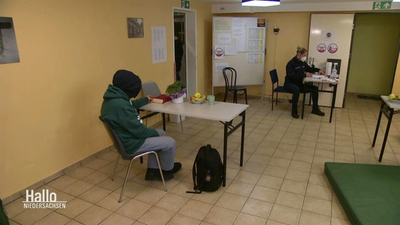 Zwei Personen sitzen in einer Wärmeunterkunft für Obdachlose in Hannover.  