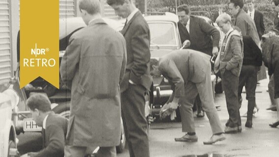 Pressevertreter schrauben an ihren Autos vor einer Alsterrallye 1964  