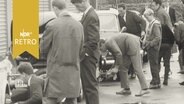 Pressevertreter schrauben an ihren Autos vor einer Alsterrallye 1964  