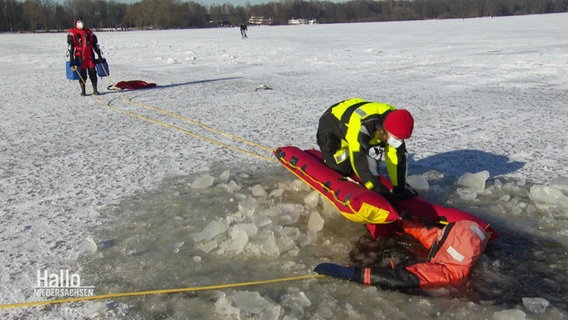 Jemand rettet eine Person aus einem Eisloch auf einem See  