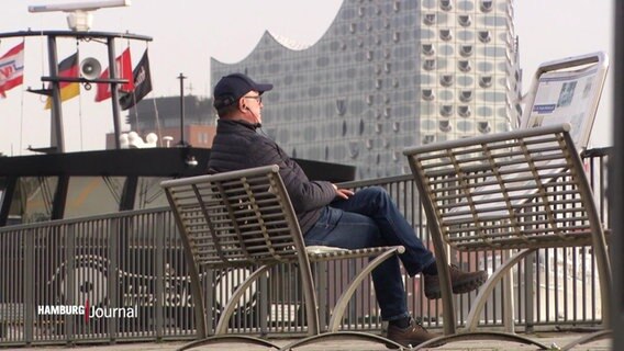 Ein Mensch sitzt am Hamburger Hafen.  