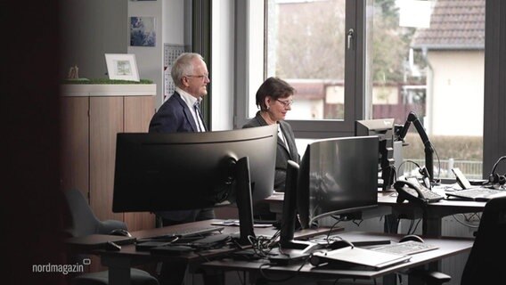 Die Geschäftsführer Katharina und Michael Clausohm hinter Computerbildschirmen.  