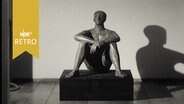 Männliche Skulptur, auf dem Boden sitzend, in einer Ausstellung 1964  