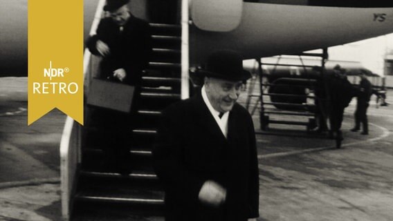 Ministerpräsident Georg Diederichst geht von der Gangway eines Flugzeugs auf das Rollfeld (1964)  