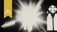 Foto in einer Fotografie-Ausstellung 1964: Ein Kirchenfenster, daneben strahlt ein Blitz oder die Sonne in die Kamera  