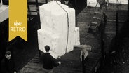 Entladung eines Frachtschiffes, Bündel an einem Kranhaken (1964).  