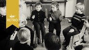 Morgenkreis in einer Kindergruppe mit Erzieherin, Kinder klatschen in die Hände (1964)  