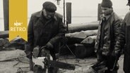 Bauarbeiter mit Kettensäge bei Arbeiten an einem Holzpfahl an der Mole von Dagebüll 1964  