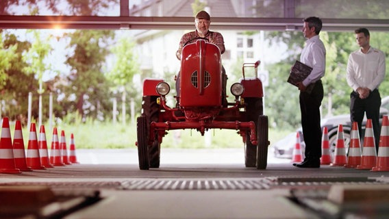 Ein Mann sitzt auf einem roten Traktor. © Screenshot NDR 