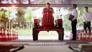 Ein Mann sitzt auf einem roten Traktor.  