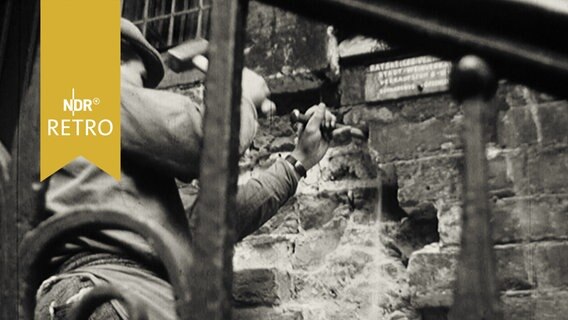 Maurer mit Hammer und Meißel an historischer Wand bei Renovierung (1964, Rathaus Bremen)  