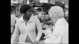 Eine junge schwarze Frau unterhält sich mit einer älteren weißen Frau.  