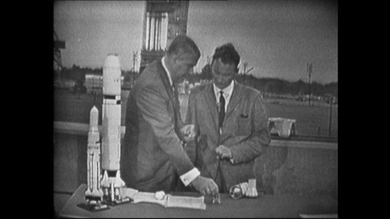 Zwei Männer vor einem Raketen-Modell.  