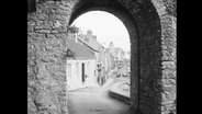 Blick durch einen Torbogen auf eine Straße in Wales.  