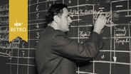 Ein Dozent an der Ingenieursschule schreibt in Tabellen an einer großen Tafel (1962)  